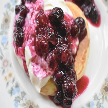 Scotch Pancakes (Drop Scones) on a plate served with yoghurt and a blueberry sauce.